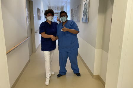 Teamomat: Pflegefachkraft und Arzt geben sich im Flur die Hand