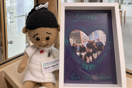 Teamomat: Handpuppe in Krankenschwester-Uniform neben Bilderrahmen