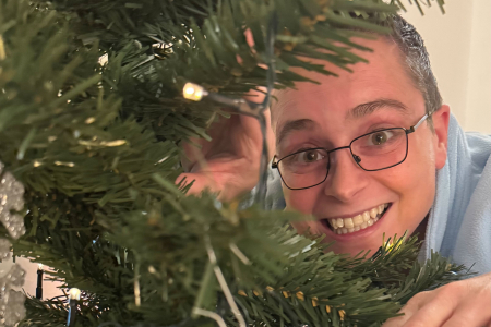 Lustige Kollegin versteckt sich hinter dem Weihnachtsbaum