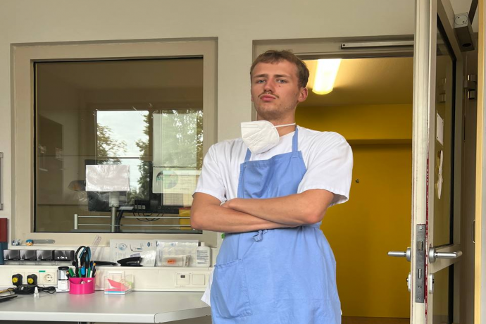 Teamomat: Junger Mann mit Schürze und skeptischem Blick